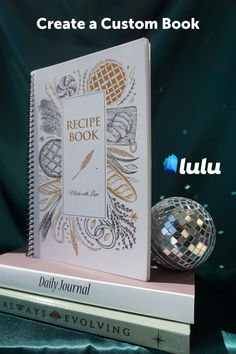 the recipe book is sitting on top of two books with disco balls in front of it