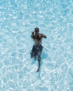 a man is swimming in the water with his cell phone up to his ear and wearing a tie