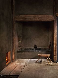 an empty room with a bench and fire place