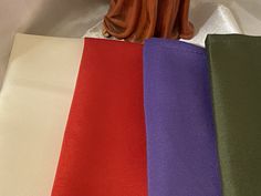 four different colors of cloth with a statue in the middle one is red, purple, and green