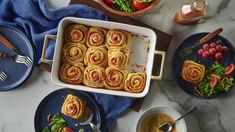 a table topped with plates and bowls filled with food next to utensils on top of a marble counter