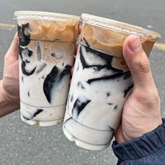 two people holding up cups with liquid in them