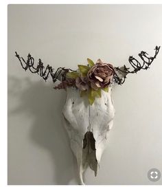 an animal skull with flowers on it's head and barbed wire around its neck