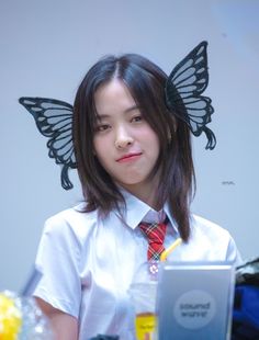 a young woman with a butterfly on her head is looking at a laptop computer screen