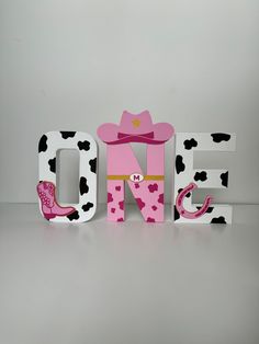 the word one is decorated with pink and black polka dots, cowboy boots, and a cow print