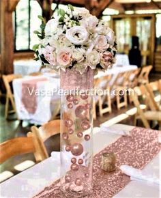 a vase filled with flowers sitting on top of a table covered in white and pink decorations