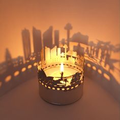 a candle that is lit up in the shape of a cityscape with buildings on it