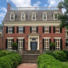 a large red brick house with black shutters on the front and stairs leading up to it