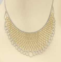 "A unique and beauiful vintage beaded drape necklace. It is well crafted from solid 14k yellow and white gold with a fine polished finish. The chain is a white gold double beaded strand with a a lobster clasp, the wide centerpiece is outlined with white gold, the end in a fancy woven design, set between the white gold is a woven design of beaded yellow gold set in a lovely liquid bib style. This amazing necklace look and feel fabulous around the neck. Will compliment a formal attire. Material: 1 Gold Beaded Chain Jewelry For Evening, Gold Jewelry With Beaded Chain For Evening, Elegant Bib Necklace With Beaded Chain, Elegant Gold Necklace With Silver Beads, Elegant White Jewelry With Ball Chain, Elegant White Ball Chain Necklace, Elegant Gold Bib Necklace With Beaded Chain, Formal Gold Necklaces With Silver Beads, Formal Silver Necklace With Gold Beads