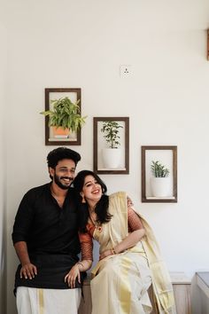 a man and woman sitting next to each other in front of pictures on the wall