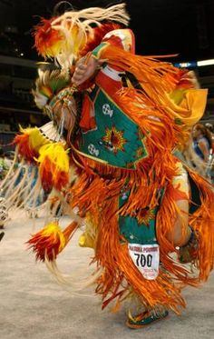 a man in an orange and green costume is dancing with his hands on his hips