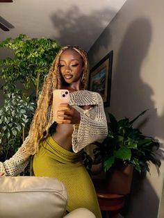 a woman taking a selfie with her cell phone in front of some potted plants