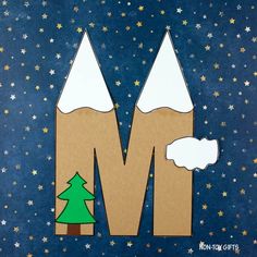 the letter m is made out of cardboard and has snow on top of it, with a tree in the middle