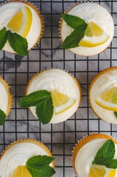 lemon cupcakes with white frosting and fresh mint leaves on a cooling rack