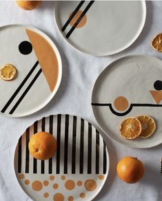 three plates with oranges on them sitting on a white table cloth next to an orange slice