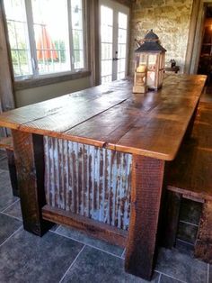 a large wooden table sitting in front of a window next to a stone flooring wall