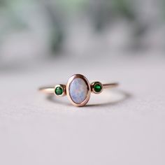 Cabochon genuine opal with two Tsavorite garnet accents. Customizable ring This pearly white opal symbolize a mother with two child. Customizable birthstone available. Solid 14k gold with genuine gemstones. Yellow gold and rose gold available. 14k fully hallmarked. Approx 1.6mm band width with 4x6mm opal, 1.5mm green garnet. LEAD TIME: Made to order will take 10-14 days. All of our jewelry will arrive in custom packaging ready for gift giving. FOLLOW US ON: Instagram: @roseandchoc Facebook: /Ros Opal Aquamarine Ring, Oval Tsavorite Ring With Gemstone Accents, Fine Jewelry Opal Ring Oval Cabochon Birthstone, Fine Jewelry Opal Oval Cabochon Ring, Round Opal Chrysoprase Ring, Fine Jewelry Rings With Ethiopian Opal Birthstone, Round Chrysoprase Opal Ring, Fine Jewelry Ethiopian Opal Birthstone Rings, Fine Jewelry Chrysoprase Rings For Anniversary