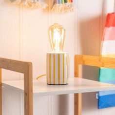 a small lamp sitting on top of a white table next to a wooden chair and wall