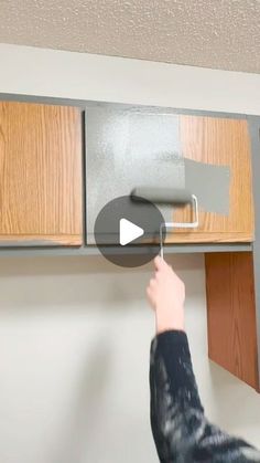 a person is painting the kitchen cabinets with gray and silver paint on it's walls