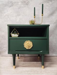 a green nightstand with two candles and a potted plant on top