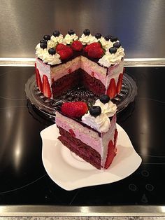 a triple layer cake with strawberries and blueberries on top is sitting on a plate