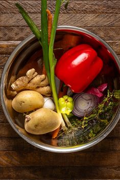 a metal bowl filled with vegetables on top of a wooden table