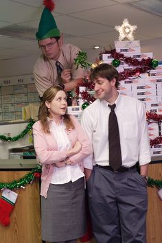 two people standing next to each other in front of a christmas tree