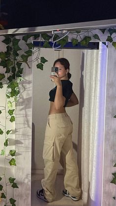 a woman taking a selfie in front of a mirror with ivy growing on it