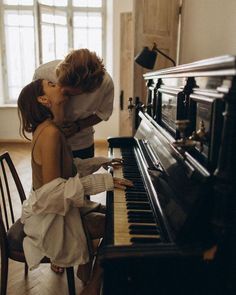 two people kissing while sitting at a piano