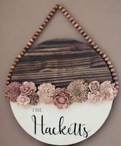 a wooden sign with flowers hanging from it's side and the words, the hakets