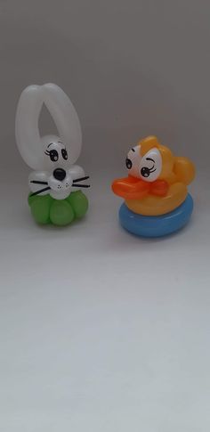 two plastic toy animals sitting next to each other on a white surface and one has an o - ring around its neck