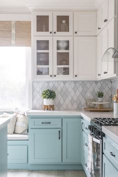 a kitchen with blue cabinets and white counter tops, along with a window seat in the middle