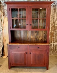 a wooden china cabinet with glass doors and drawers on the top, in front of a curtained wall