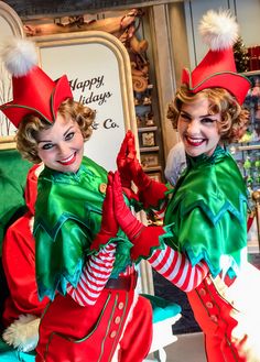 two women dressed in elf costumes posing for the camera with their hands together and smiling