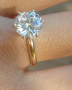 a woman's hand with a yellow gold ring and a white diamond on it