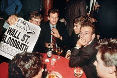 a group of men sitting at a table with drinks and signs in front of them