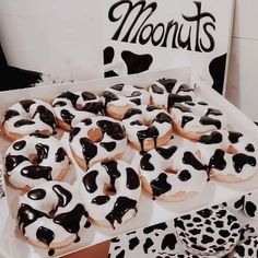 a box filled with lots of donuts covered in black and white frosting on top of a table