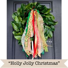 a wreath with ribbons hanging from it's side and the words holly jolly christmas