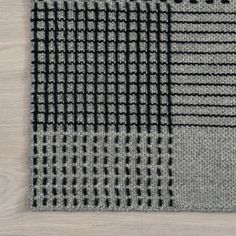 a gray and black rug on top of a wooden floor