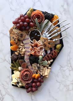 a platter filled with meats, cheeses and fruit on top of a marble counter