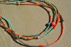 the multi - stranded beaded necklace is displayed on a wooden surface with other beads