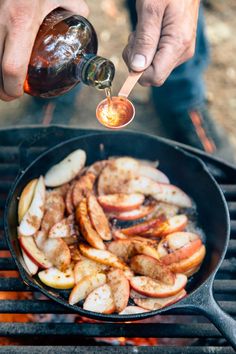 someone is cooking apples on the grill with a wooden spoon in their hand and pouring them into a skillet