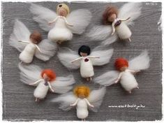 needle - felt angels with orange hair and white wings are arranged in a circle on a wooden surface