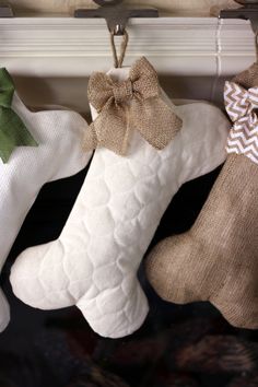 three christmas stockings hanging on a clothes line with burlocks and bows attached to them