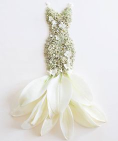 there is a white flower that has been placed in the shape of a woman's dress