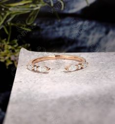 a gold ring with three stones on it sitting on a table next to a potted plant