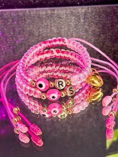 pink and gold bracelets with personalized charms are displayed in front of a purple background