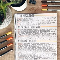 an open book with writing on it next to pens and other office supplies sitting on a table