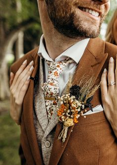 a man in a suit and tie with flowers on his lapel