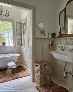 a bathroom with a tub, sink, mirror and rug on the floor in front of it